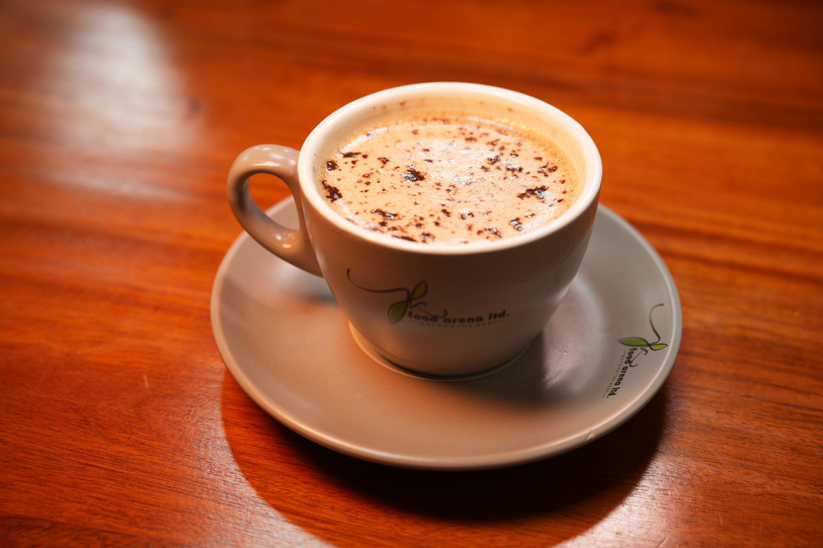 Cup of bullet coffee served in a ceramic mug on a wooden table at JK Food Arena.